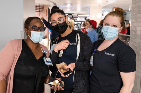 Three female employees in surgical masks stand together after receiving their food samples at the new eatery 